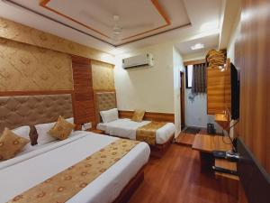 a hotel room with two beds and a television at Hotel Stay Inn in Bodakdev