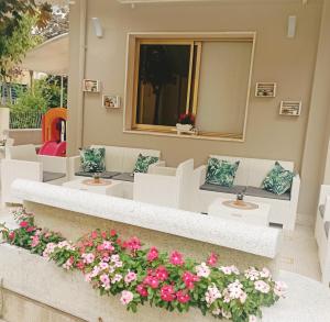 um pátio com cadeiras brancas e flores cor-de-rosa em Hotel Raul em Riccione