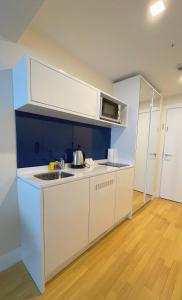 a white kitchen with a sink and a microwave at Apartments Black Sea Resort in Batumi
