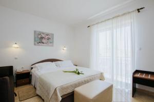 a white bedroom with a bed and a window at Hotel Vila Tina in Trogir