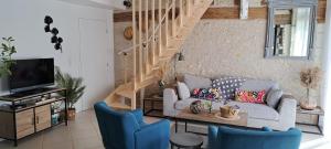 a living room with a couch and a staircase at Chambre d'hôte La Voilerie du Cher in Saint-Georges-sur-Cher