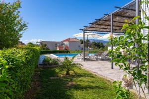 a backyard with a swimming pool and a pergola at Modern apartment with private pool near Split in Podstrana