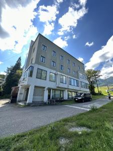 a large white building with a car parked in front of it at Arise Hakuba Lodge in Nagano