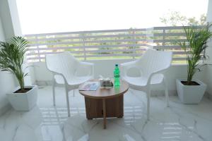 een kamer met witte stoelen en een tafel met een fles erop bij The City Crown Bilaspur in Bilāspur