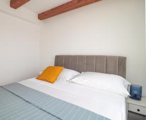 Bett mit orangefarbenem Kissen und weißen Kissen in der Unterkunft Laura Apartments in Brodarica + 186 Fotos