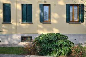 a building with three windows and a bush in front of it at Il Nido di legno in Udine