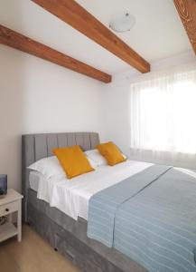 ein Schlafzimmer mit einem großen Bett mit orangefarbenen Kissen in der Unterkunft Laura Apartments in Brodarica
