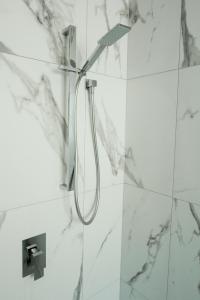 een douche in een witte badkamer met marmeren muren bij New and Cosy on Salisbury Street - City Centre in Christchurch