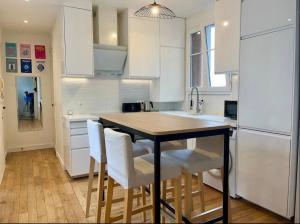 een keuken met witte kasten en een tafel en stoelen bij Parisian charm flats in Levallois-Perret