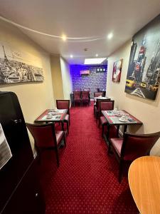 un restaurante con mesas y sillas y alfombra roja en Hotel Victor Hugo, en Clamart