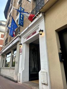 un bâtiment avec des drapeaux sur son côté dans l'établissement Hotel Victor Hugo, à Clamart