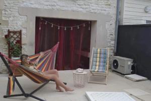 una donna seduta su un'amaca su un patio di Grande chambre avec lit Bambou et canapé lit a Chef-Boutonne