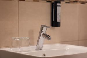 a bathroom sink with two glasses and a faucet at Hotel & Gästehaus Im Ziegelweg KLIMATISIERT Eintrittskarten für den Europa-Park erhalten Sie garantiert über uns in Rust