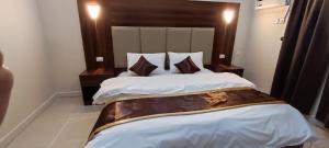 um quarto com uma cama grande com lençóis brancos e almofadas em شقق العييري المخدومة الباحة 02 em Al Baha