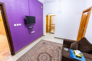 uma sala de estar com uma parede roxa e um sofá em شقق العييري المخدومة الباحة 02 em Al Baha