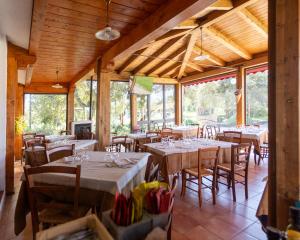 a dining room with tables and chairs and windows at Monte Pirastru in Nughedu San Nicolò