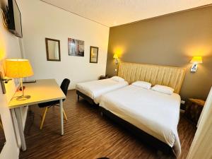 a hotel room with two beds and a desk at Hotel Italia in Tours