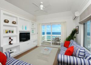 a living room with a blue couch and a television at Coastal Haven: Charming Beachfront Cottage with Pool in James Cistern