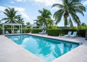una piscina con 2 sillas y palmeras en Coastal Haven: Charming Beachfront Cottage with Pool, en James Cistern