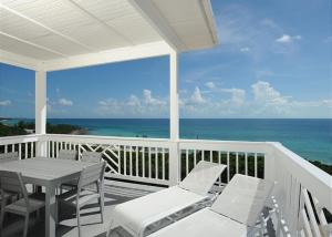 a porch with a table and chairs and the ocean at Coastal Haven: Charming Beachfront Cottage with Pool in James Cistern