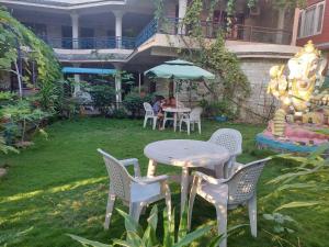 a table and chairs in a yard with a table and umbrella at Blue Planet Lodge & Restaurant in Pokhara