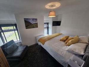 1 dormitorio con cama, sofá y ventana en cosy cottage in snowdonia en Brynkir