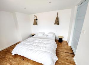 ein weißes Bett in einem weißen Zimmer mit Holzböden in der Unterkunft Superbe duplex 50 mètres de la plage in Le Portel