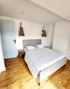 Schlafzimmer mit einem weißen Bett und Holzboden in der Unterkunft Superbe duplex 50 mètres de la plage in Le Portel