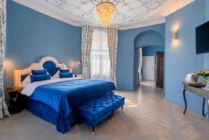 a blue bedroom with a large bed and a chandelier at Schloßhotel Althörnitz in Bertsdorf