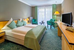 ein Hotelzimmer mit einem großen Bett und einem TV in der Unterkunft Schloßhotel Althörnitz in Bertsdorf