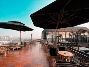 balcón con mesas, sillas y sombrillas en Happiest Homestay 1 - Manor Crown Hue en Hue
