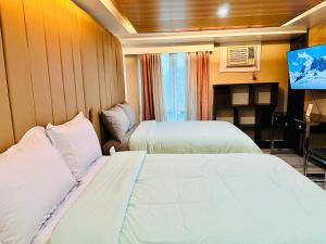 Habitación de hotel con 2 camas y TV de pantalla plana. en Feels Like Home Condos Abreeza Place Tower 1 & 2 en Davao