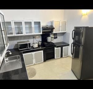 una cucina con armadi bianchi e frigorifero in acciaio inossidabile di Araliya Uyana Apartments - Two Bed Room House a Ratmalana