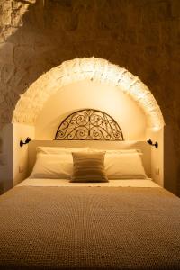 1 dormitorio con 1 cama en una pared de piedra en Trullo Jalè - Boutique Apartments, en Ostuni