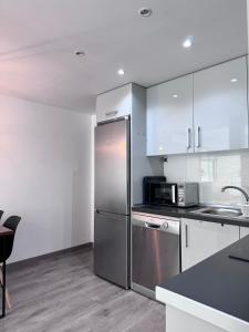 una cocina con nevera de acero inoxidable y armarios blancos en SumaLoft Prensa, en Málaga