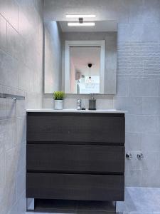 un baño con lavabo y espejo en SumaLoft Prensa, en Málaga