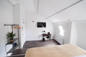 ein weißes Zimmer mit einem Bett und einem Schreibtisch in der Unterkunft Sgwâr in Menai Bridge