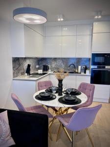 a kitchen with a table and purple chairs at White Pearl Apart in Rogowo