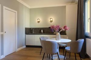 una cocina con una mesa con sillas y un jarrón de flores en Eden Rooms, en Stresa 11 fotos más