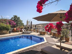 a swimming pool with an umbrella and chairs at Cyprus Villages Hotel & Restaurant - Central Location - Bed & Breakfast - With Access To Pool And Stunning Views in Tochni