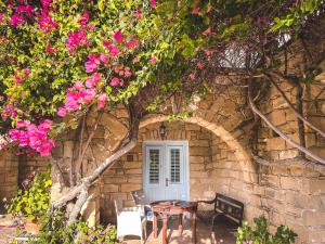 a table and chairs in front of a stone wall with pink flowers at Cyprus Villages Hotel & Restaurant - Central Location - Bed & Breakfast - With Access To Pool And Stunning Views in Tochni