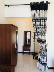 una habitación con una cortina en blanco y negro y un espejo en Crocotopond, en Arugam Bay