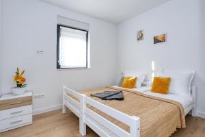 a white bedroom with a bed and a window at Apartment Wali in Nin