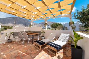 a patio with a table and chairs under a wooden roof at DP Homes Beachside in Santorini in Perissa