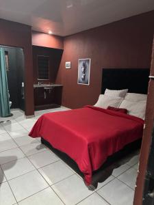 1 dormitorio con 1 cama grande con manta roja en X-MOTEL VOSLOORUS, en Vosloorus