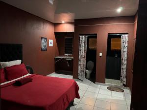 1 dormitorio con cama roja y lavamanos en X-MOTEL VOSLOORUS, en Vosloorus