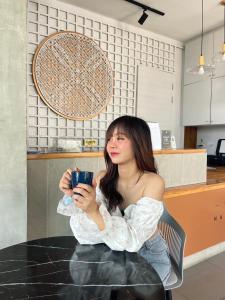 a woman sitting at a table holding a coffee cup at Villa Mahaphrom in Nan