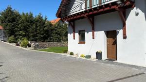 a white building with a balcony and a door at ADUSIÓWKA in Stronie Śląskie