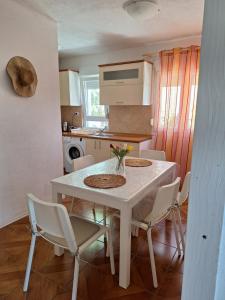 Biały stół jadalny z krzesłami i kuchnia w obiekcie Apartman Anchi w mieście Zadar