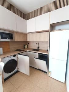 una cucina con armadi bianchi, lavandino e lavastoviglie di Apartamento Cabo de Palos - La Manga con Aire Acondicionado a Cartagena